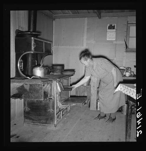 Mrs. Wardlow baking corn bread in her dugout basement home. Dead Ox Flat, Malheur County, Oregon