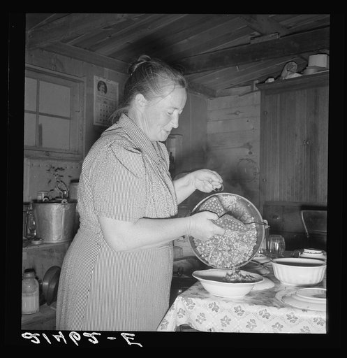 Mrs. Wardlow getting dinner after church in her basement dugout home. Dead Ox Flat, Malheur County, Oregon
