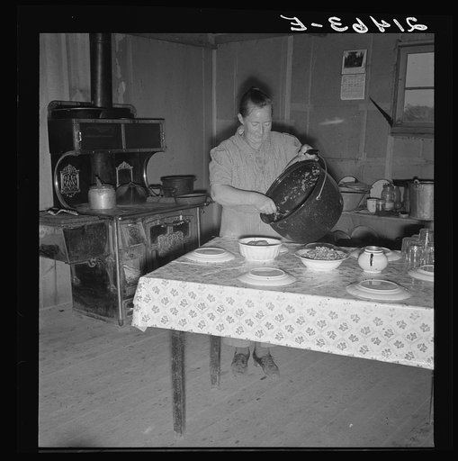 Mrs. Wardlow getting dinner after church in her basement dugout home. Dead Ox Flat, Malheur County, Oregon