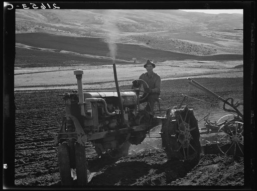Young Idaho farmer plowing in the fall of the year while the other members of the Ola self-help sawmill co-op are working in the sawmill. The tractor does work for five member families. Gem County, Idaho