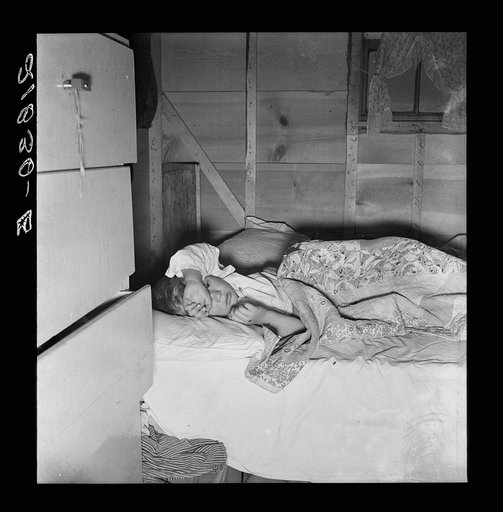 Sick child of young couple who migrated to Oregon from Amarillo, Texas, five months ago. Their home is now this house trailer. Mother says "He's been ailin all his life, you might say." FSA (Farm Security Administration) mobile camp, Merrill, Klamath County, Oregon