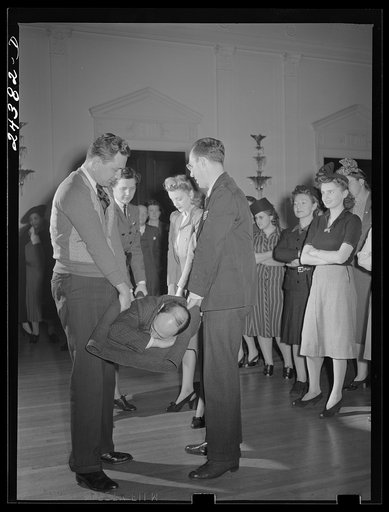 Civilian defense volunteers receiving instruction in proper care for man with spine injury. First aid class. New York City