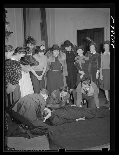 Untitled photo, possibly related to: Civilian defense volunteers receiving instruction in proper care for man with spine injury. First aid class. New York City