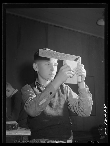 Boy using right angle square in woodworking shop at the homestead school. Dailey, West Virginia
