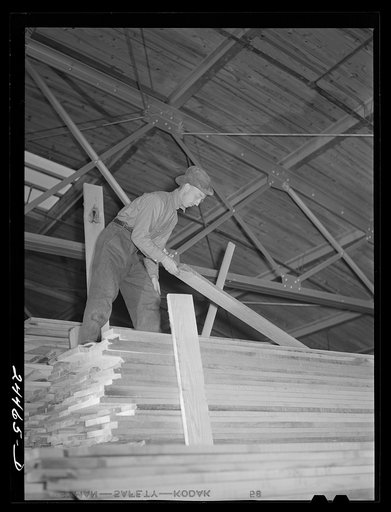 Worker unloading lumber from stacks. Dimension lumber plant. Dailey, West Virginia