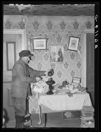 John Dudeck lighting a lamp in his home. Dalton, New York, Allegany County