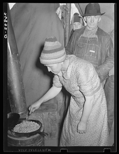 Wife of evicted sharecropper in tent along highway cooking beans obtained from surplus commodities. New Madrid County, Missouri