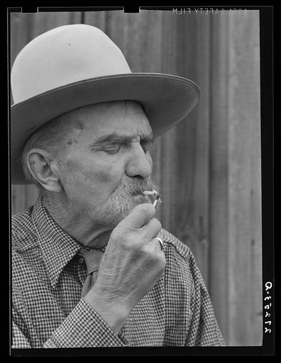 Frank Latta lighting a hand-rolled cigarette. Bozeman, Montana