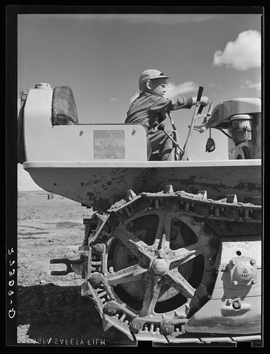 Wheat farmer's son playing with tractor. Cascade County, Montana