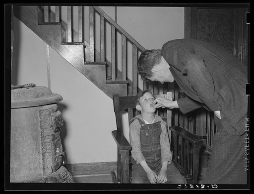 Doctor hired by farmers' cooperative health association examining a sick boy. Fairfield Bench Farms, Montana