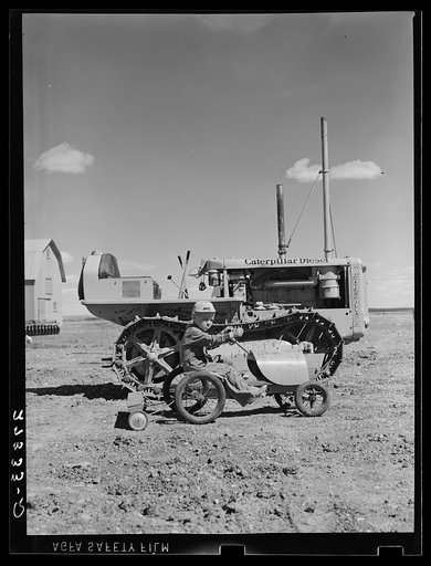 Johnnie Sheffels with his toy tractor and seed drill. Cascade County, Montana