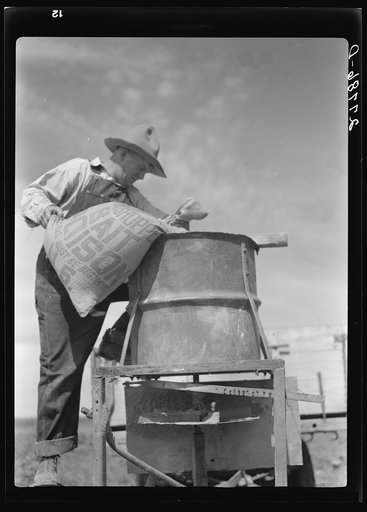 Untitled photo, possibly related to: Farmer loading spreading device with grasshopper poison. Forsyth, Montana