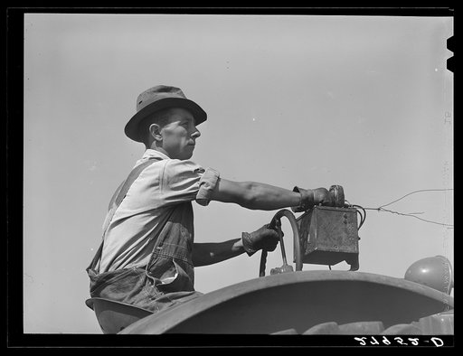 Hired hand tunes in radio on tractor while cutting hay. Kimberley farm, Jasper County, Iowa