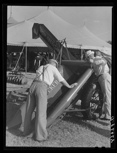 Farmer examines new corn picker. Iowa State Fair, Des Moines, Iowa