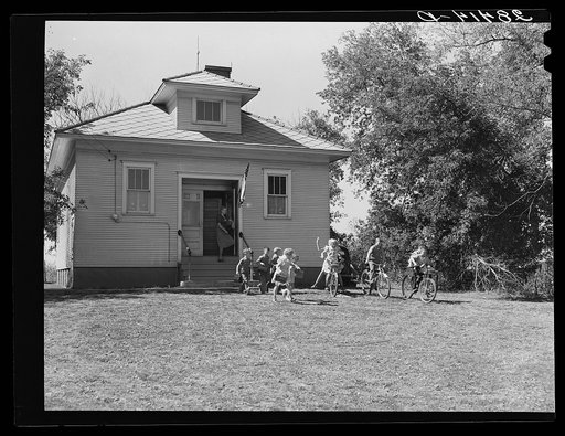 Children wave goodby to their teacher as they leave school. Grundy County, Iowa