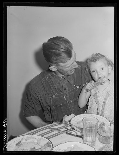 Thomas Beede and small daughter at the dinner table in their home. Western Slope Farms, Colorado