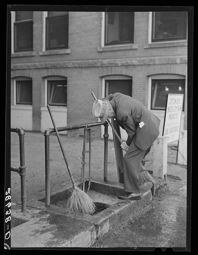 Cattle buyer cleaning his shoes after trip through the stockyards. Denver, Colorado