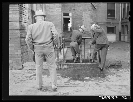 Men cleaning their boots after visit to stockyards. Denver, Colorado