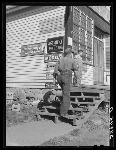 Untitled photo, possibly related to: Carrying bags of flour out of general store. Lamoille, Iowa