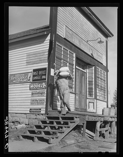 Carrying bags of flour out of general store. Lamoille, Iowa