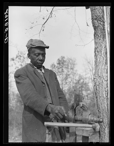 Evicted sharecropper fixes his axe. Butler County, Missouri