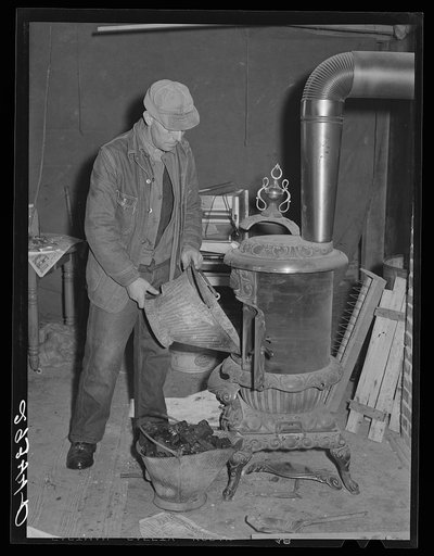 O.G. Haubeil emptying coal scuttle into stove. Ross County, Ohio