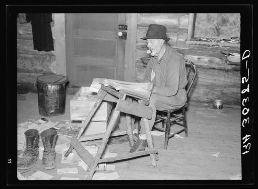 William Besson, veteran iron ore prospector and timber cruiser, examining geological surveys in his cabin near Winton, Minnesota