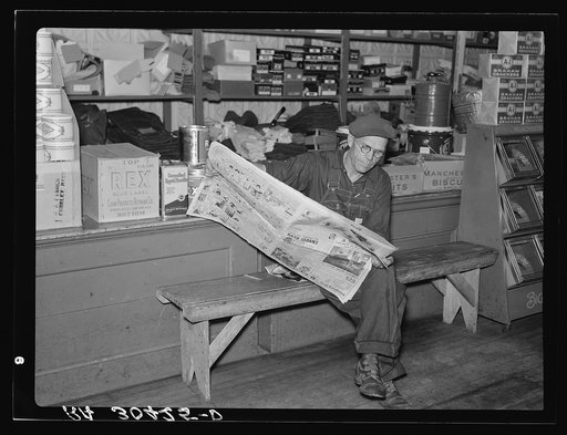 Resident of Funkley, Minnesota, reading newspaper in general store