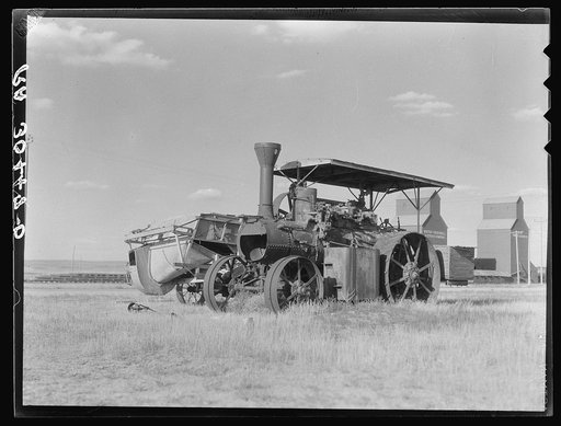 Idle threshing with empty elevators in the background. Williams County, North Dakota