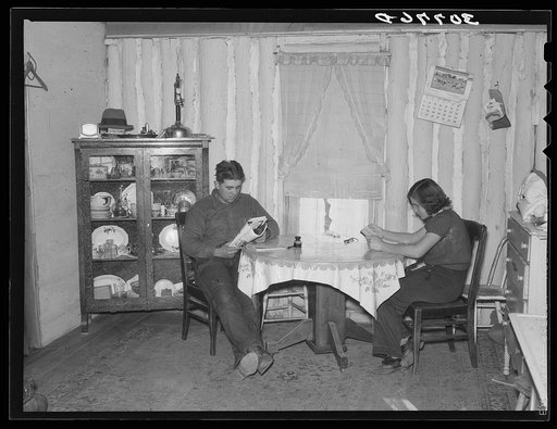 Children of farmer reading in dining room. Note construction of the walls. Williams County, North Dakota