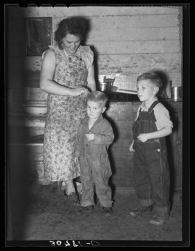 Mother dressing up her children. Farm home, Williams County, North Dakota