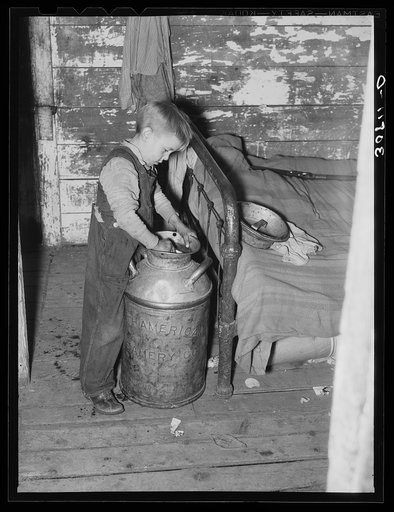 Son of Joe Kramer dipping water from a milk can. Near Williston, North Dakota
