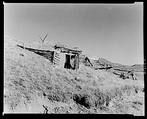 "Hominy" Thompson in the door of the root cellar he built. In the early railroad days the Soo line was being built through this country. He moved his house where the railroad was to be built and with his shotgun delayed progress of the railroad for a week