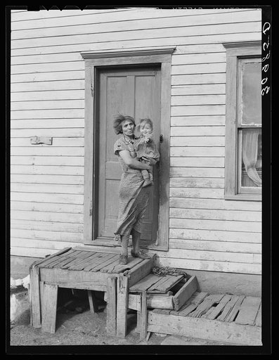 Mrs. John Baker and baby on steps of farm home. Divide County, North Dakota