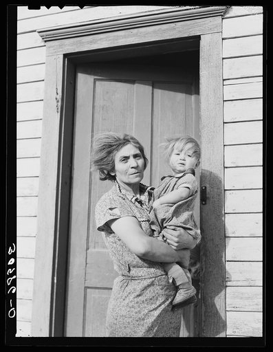 Mrs. John Baker and baby on steps of farm home. Divide County, North Dakota