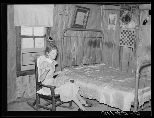 Southeast Missouri Farms. Sharecropper's daughter sewing in combination living room/bedroom of shack home. La Forge project, Missouri