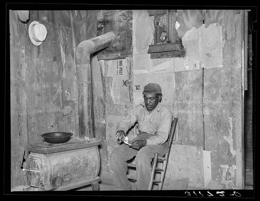 New Madrid County, Missouri. Sharecropper rolling cigarette in living room of shack home
