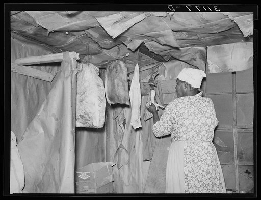 Southeast Missouri Farms. Wife of sharecropper cutting piece of fatback from slab in kitchen of shack home