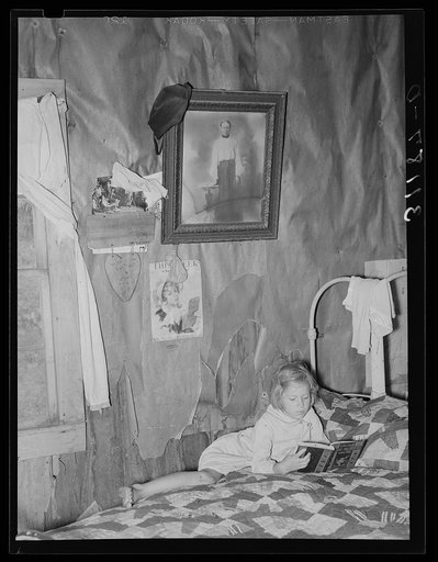 Southeast Missouri Farms. Child of sharecropper reading on bed in living room