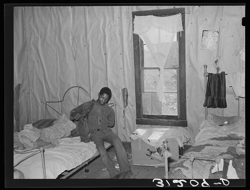Southeast Missouri Farms. Son of sharecropper getting dressed in bedroom shack