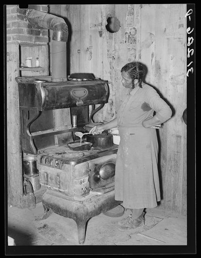 Southeast Missouri Farms. Woman preparing gravy in corner of kitchen sharecropper cabin