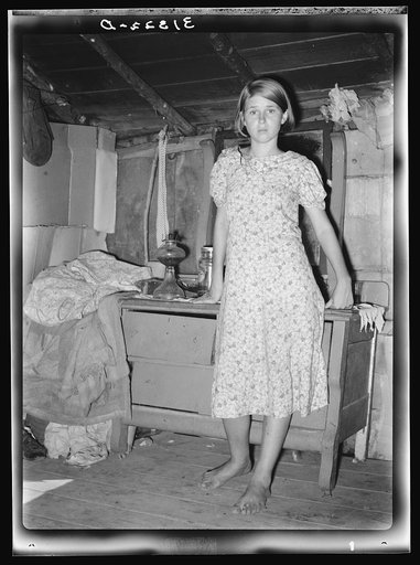 Girl standing in front of bureau in shack home. Tin Town, Caruthersville, Missouri