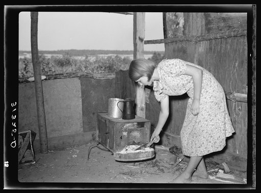 Girl tending fire in shack home. Tin Town, Caruthersville, Missouri
