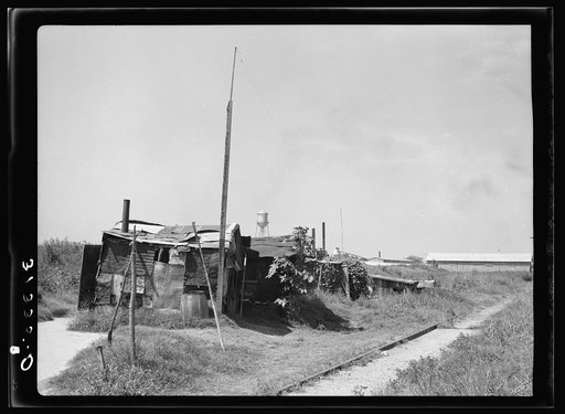 Line of shacks in Tin Town, Caruthersville, Missouri. Industrial plant in the background