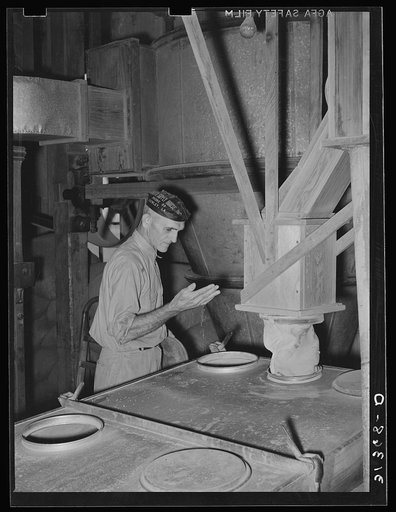 Worker inspecting progress of screening in milling operation. State rice mill, Crowley, Louisiana