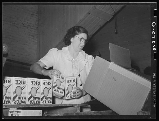 Removing packages of rice from conveyer to place them in fiber cartons.  State rice mill, Abbeville, Louisiana