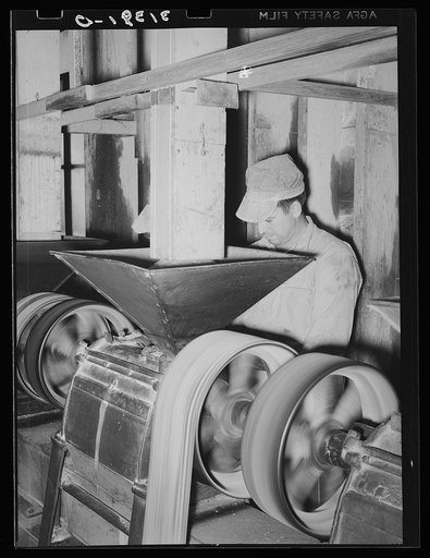 Man working at machine for removing bran from kernel. Crowley, Louisiana