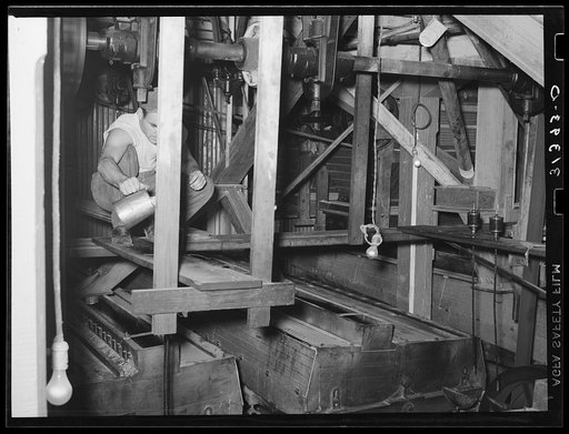 Man oiling machine used for screening rice. State rice mill, Crowley, Louisiana