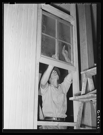 Member of Lake Dick cooperative association installing window of partition in general store. Lake Dick Project, Arkansas