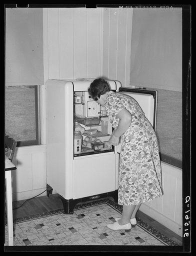 Housewife removing articles from electric refrigerator in farm home. Lake Dick Project, Arkanas